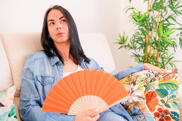 Una donna seduta nella sua casa, che soffre di un'ondata di calore in cerca di sollievo dalle temperature calde e umide - Foto, immagini