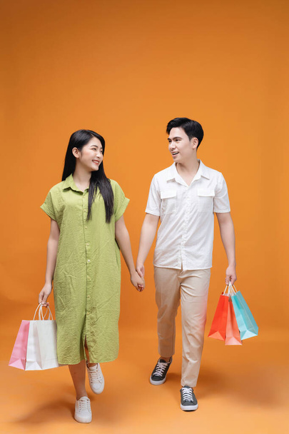 Joven pareja asiática sosteniendo bolsa de compras en fondo - Foto, Imagen