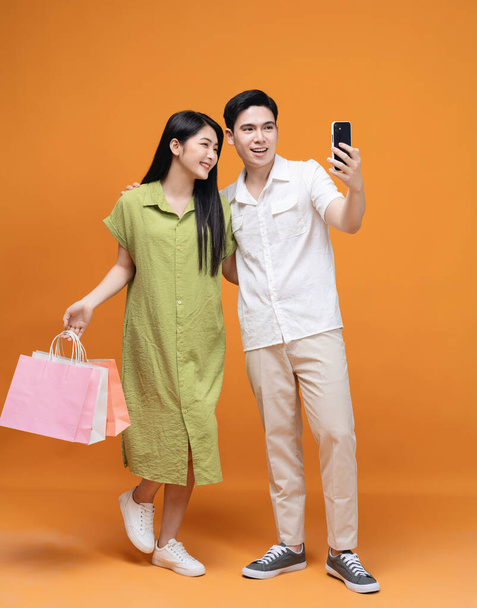 Young Asian couple holding shopping bag on background - Photo, image
