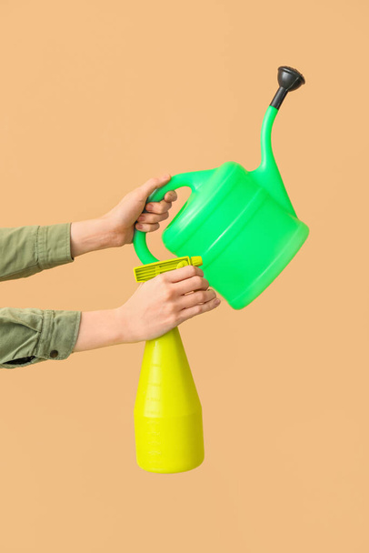 Female gardener with watering can and spray bottle on beige background - Foto, immagini