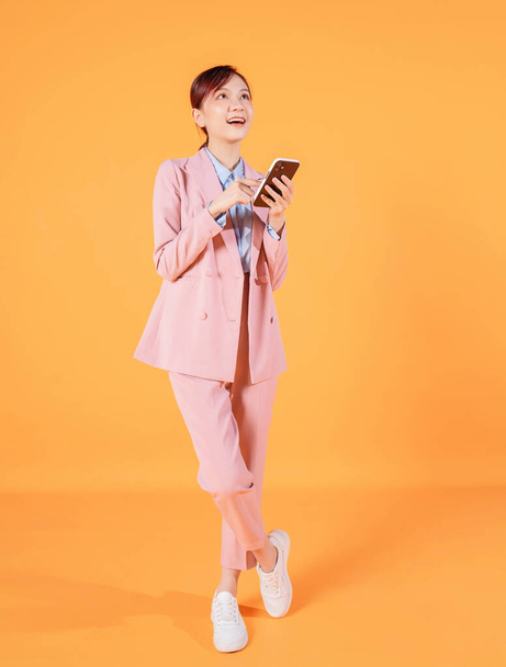 Молода азіатська бізнес-леді, яка користується смартфоном на задньому плані - Фото, зображення