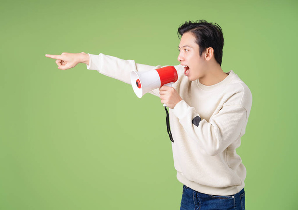 Image d'un jeune homme asiatique tenant un haut-parleur sur fond - Photo, image