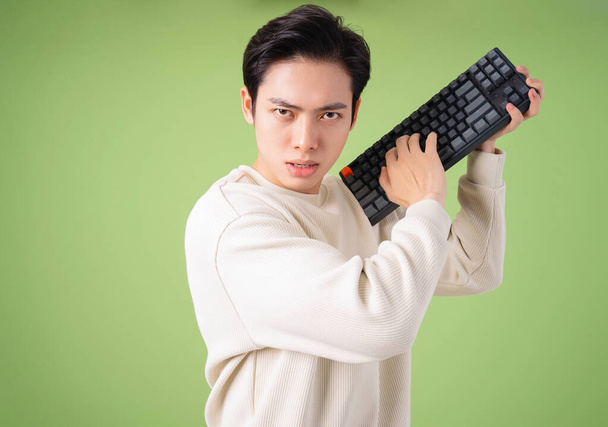 Bild eines jungen, wütenden Asiaten mit Tastatur - Foto, Bild