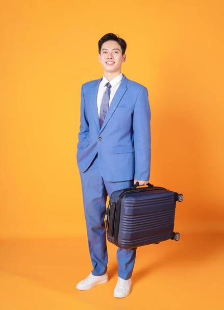 Imagem do jovem homem de negócios asiático segurando mala em segundo plano - Foto, Imagem