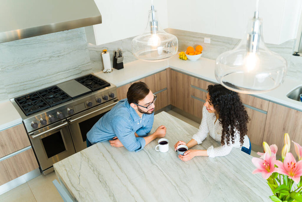 Top view of a happy couple drinking coffee on the granite kitchen island in the morning while looking in love - Photo, image