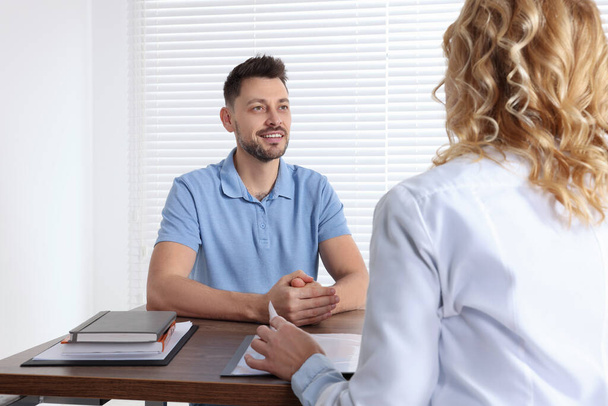 Doctor consulting patient at table in clinic - Foto, imagen