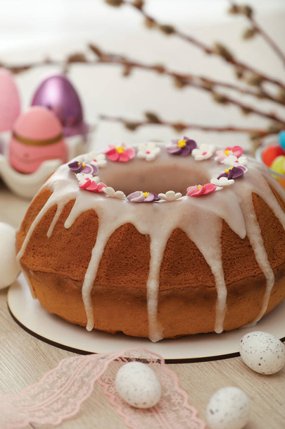 Delicious Easter cake decorated with sprinkles near painted eggs on white wooden table - Foto, Bild