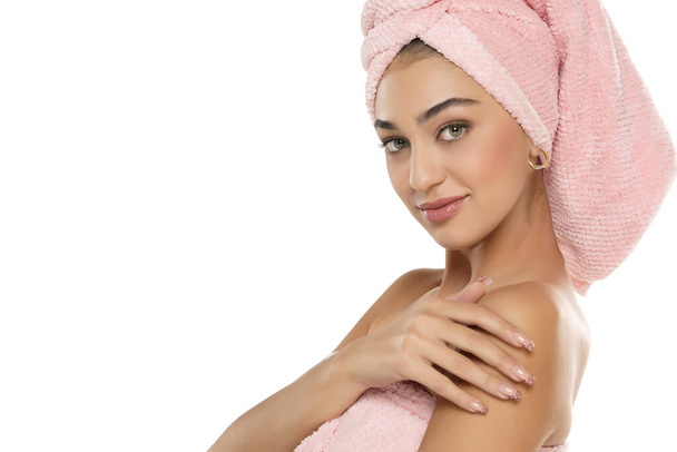 Une jolie jeune femme souriante avec une serviette sur la tête posant sur un fond de studio blanc - Photo, image