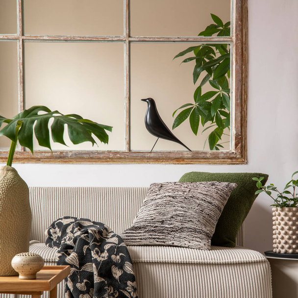 Warm and cozy living room interior with beige modular sofa, big window, patterned pillows, braided plaid, black bird, vase with leaves, plants,  and personal accessories. Home decor. Template.  - Fotografie, Obrázek