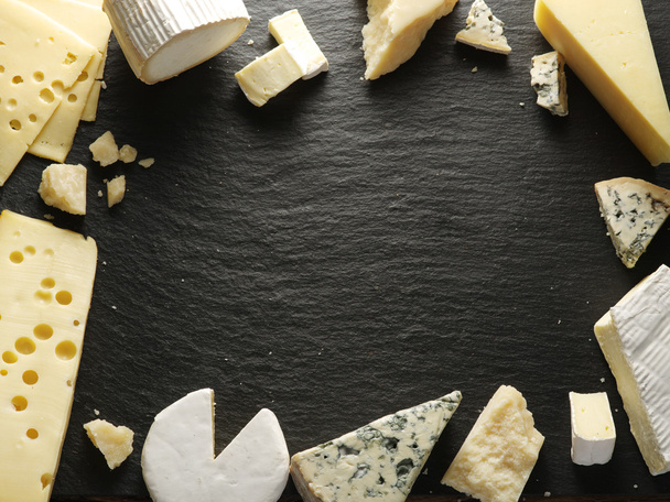Different types of cheeses arranged as a frame on black board. - Valokuva, kuva