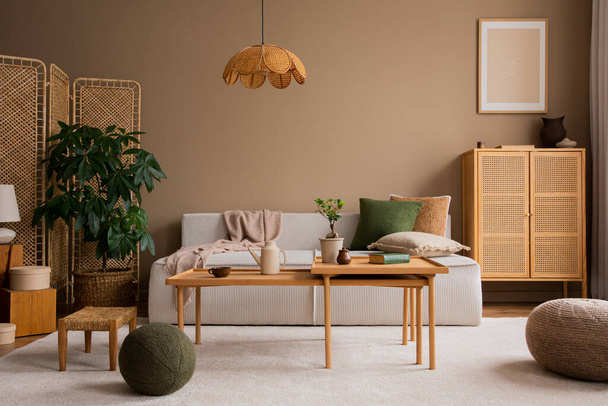 Interior design of living room with modular  sofa, wooden coffee table, rattan sideboard, green pillow, lamp, brown pouf, beige rug, plants and personal accessories. Home decor. Template.  - Zdjęcie, obraz