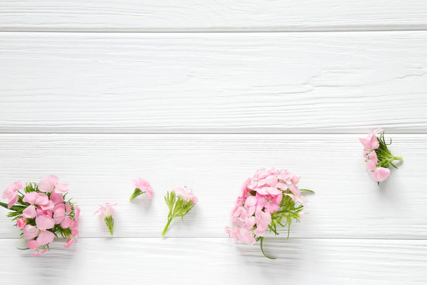 Pequeñas flores rosadas sobre fondo rústico de madera blanca - Foto, imagen