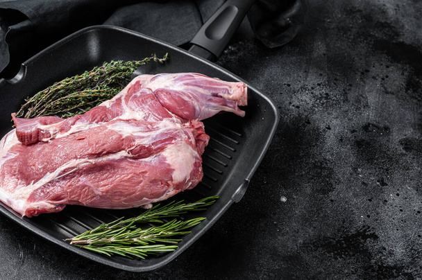 Ready for cooking lamb whole shoulder, raw leg meat on a grill pan with spices. Black background. Top view. Copy space. - Foto, Imagem