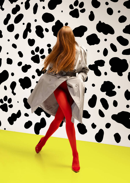 Fashionable stylish girl in grey coat and bright red tights in motion over animal print pattern background. Expressive fashion. Concept of art photography, beauty. Redhaired faceless model walking - Fotografie, Obrázek