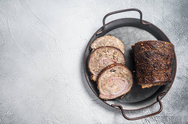 Sliced roast pork meat roulade on a steel tray. White background. Top view. Copy space. - Photo, Image