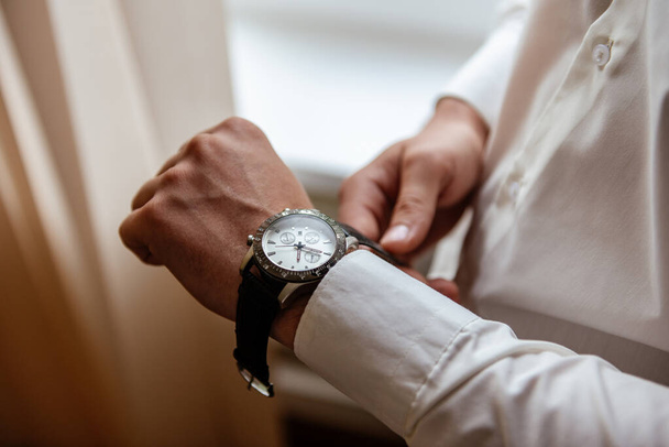 A man in a white shirt wears an expensive watch on his hand. - 写真・画像