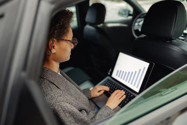 Woman manager working on laptop sitting car leather backseat on way to office. High quality photo - Photo, Image