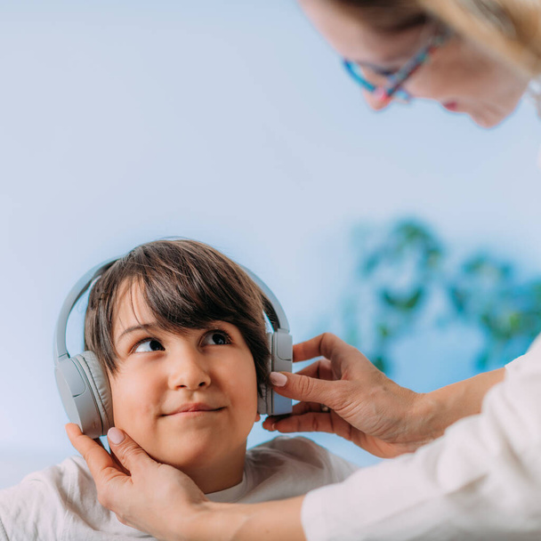 Pure toon audiometrie test, het controleren van kinderen in staat om verschillende toonhoogtes en volumes van geluid te horen. Jongen Kind met koptelefoon luisteren geluiden met verschillende toonhoogtes en volumes, reageren.  - Foto, afbeelding