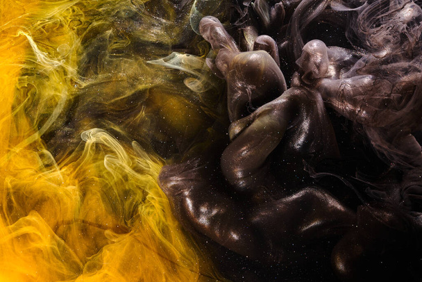 Black yellow abstract ocean background. Splashes and waves of paint under water, clouds of interstellar smoke in motion - 写真・画像