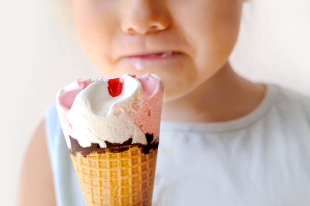 child 3 years old, going eat cold ice cream cone, strawberry dessert with fruit jam and chocolate, appetizing eating, happy childhood concept, children's delicacy, healthy and unhealthy food - Fotó, kép
