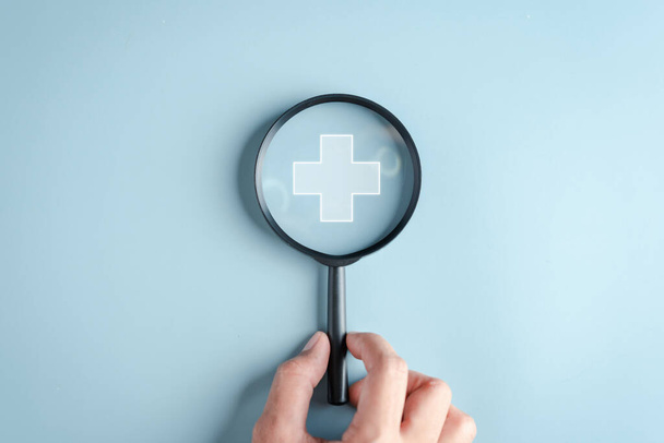 Health insurance concept. Hand people holding Magnifier focus to plus symbol and healthcare medical icon, health and access to welfare health concept. - Photo, Image
