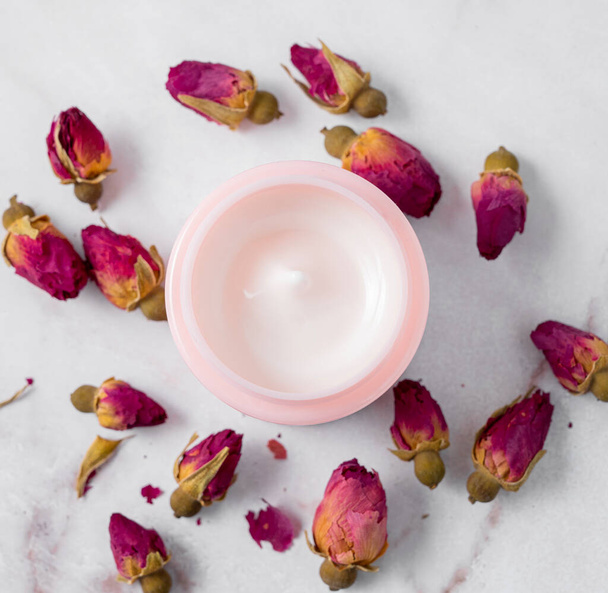 Face and body cream on a marble table close up. The concept of care cosmetics with rose. Health and beauty. Top view. - Fotografie, Obrázek