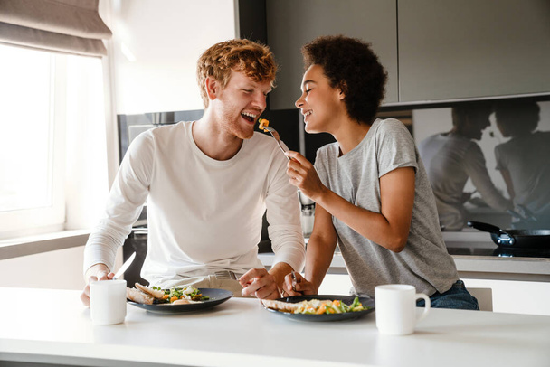 Young multinational couple smiling while having breakfast together at home - Valokuva, kuva