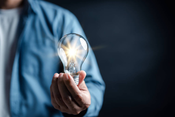 Hand man holding illuminated lightbulb, idea, innovation and inspiration with glowing virtual brain, smart intelligent creativity with bulbs, Motivation and innovation concept. - Photo, Image