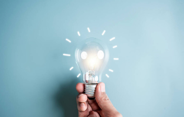 Hand man holding illuminated lightbulb, idea, innovation and inspiration with glowing virtual brain, smart intelligent creativity with bulbs, Motivation and innovation concept. - Zdjęcie, obraz