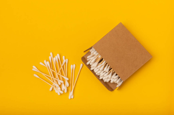 Cotton buds on a bright yellow background.Eco-friendly materials. Wooden, cotton swabs on a white background.Bamboo swabs and cotton flowers.Zero waste, plastic free lifestyle concept.Place for text. - Foto, Imagem