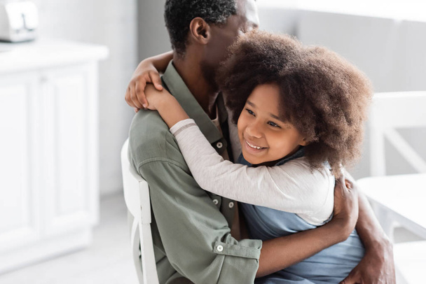 happy african american child with curly hair hugging middle aged grandfather at home  - Φωτογραφία, εικόνα