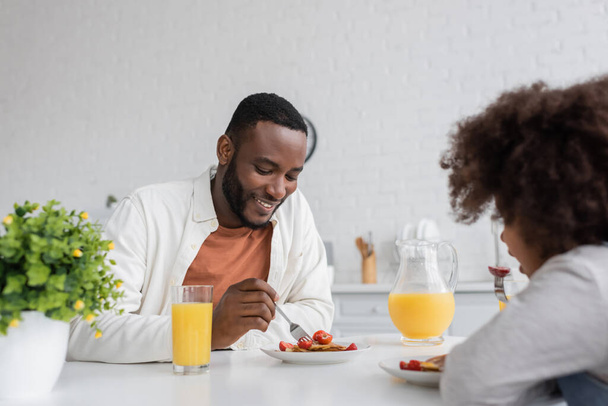 happy african american man having breakfast with curly daughter in kitchen  - Φωτογραφία, εικόνα