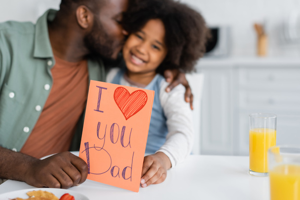 africano americano hombre besos hija y celebración de la tarjeta de felicitación con yo amor usted papá letras en padres día  - Foto, imagen
