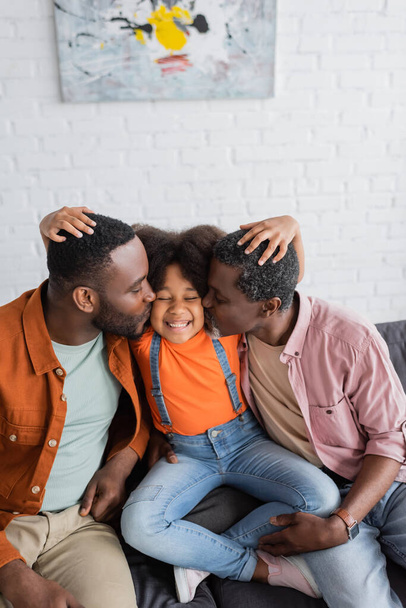 African american granddad and father kissing cheerful girl on couch at home  - Foto, imagen