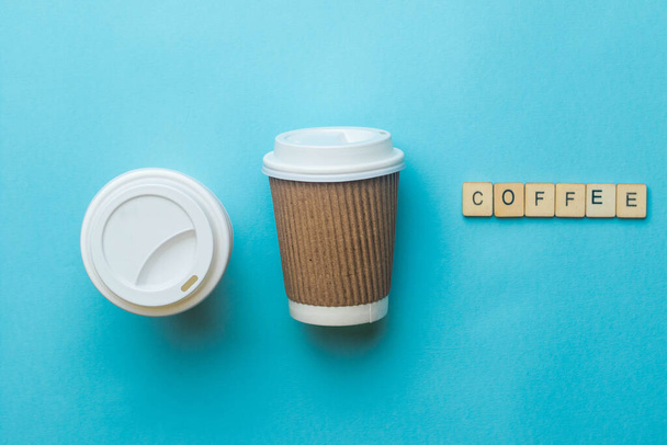 2 paper coffees cup and lid with a sign reading coffee on a blue background - Foto, Imagem