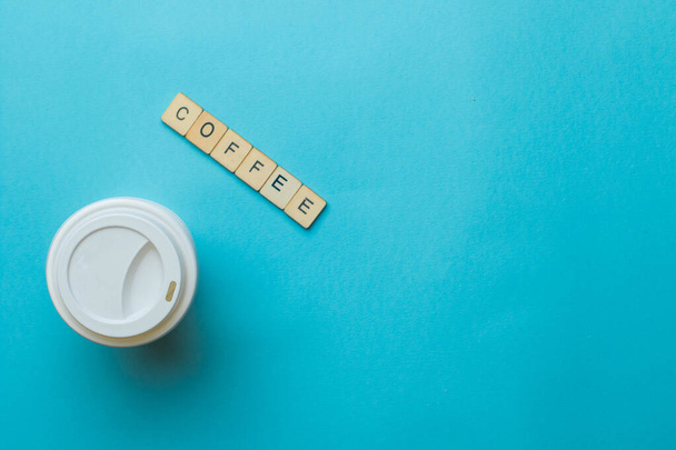 A paper coffee cup and lid with a sign reading coffee on a blue background - Foto, Bild