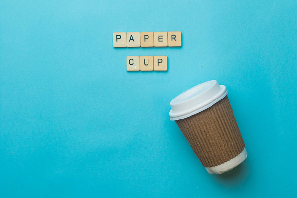 A paper coffee cup amd lid with a sign reading Paper Cup on a blue background - Photo, image