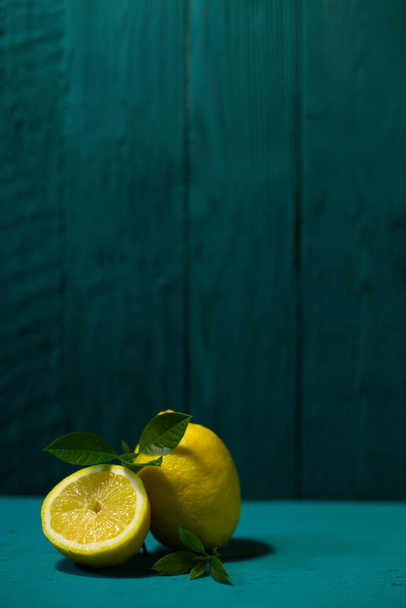 Juicy fresh lemons and leaves on a beautiful blue background - Foto, Imagen