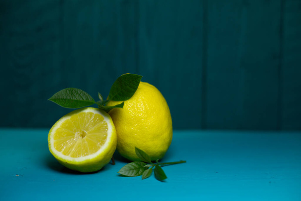 Juicy fresh lemons and leaves on a beautiful blue background - Foto, Imagen