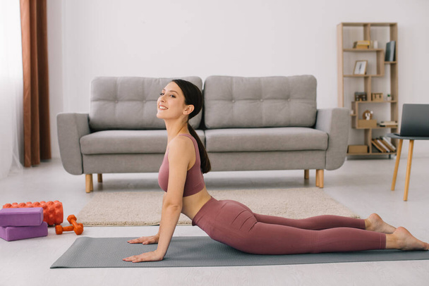 Mujer joven atractiva y saludable haciendo ejercicios mientras descansa en casa
 - Foto, imagen