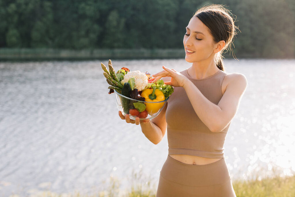 Retrato de mulher vegan feliz segurando prato de legumes frescos ao ar livre - Foto, Imagem