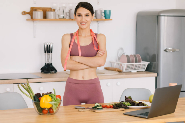 Портрет счастливой спортивной женщины-блоггера за столом со свежими овощами, концепция здорового питания - Фото, изображение