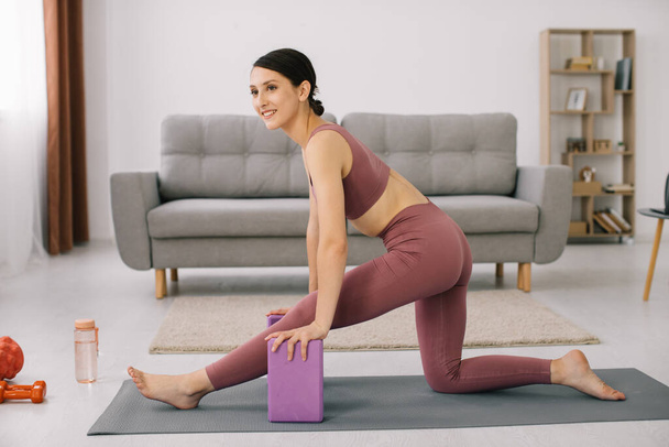 Attractive and healthy young woman doing exercises while resting at home - Φωτογραφία, εικόνα