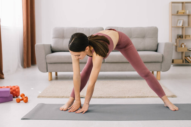 Mujer joven atractiva y saludable haciendo ejercicios mientras descansa en casa
 - Foto, imagen