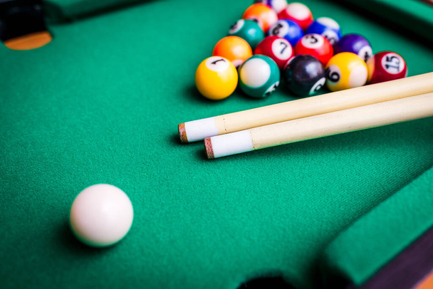Billiard sport concept.Playing billiard.Billiard cues and pyramid of multicolored snooker pool balls on green billiard table. - Photo, Image