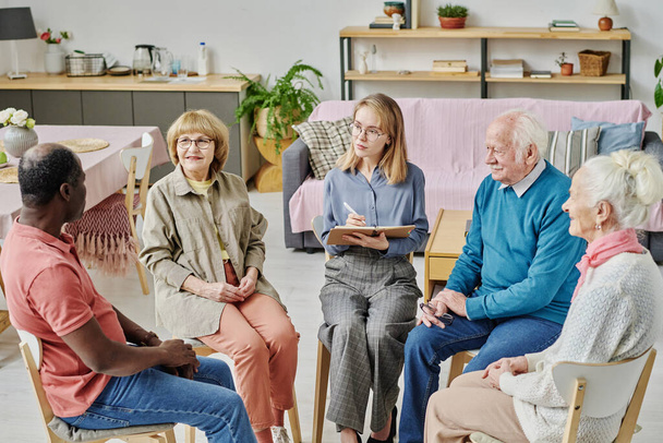 Літні люди розмовляють з психотерапевтом під час сеансу психотерапії в будинку престарілих
 - Фото, зображення