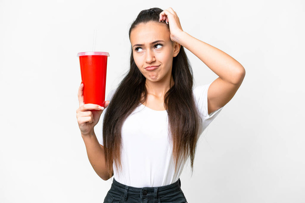 Young Arabian woman holding soda over isolated white background having doubts and with confuse face expression - Photo, Image