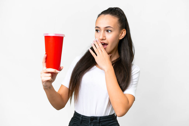 Young Arabian woman holding soda over isolated white background with surprise and shocked facial expression - Photo, Image