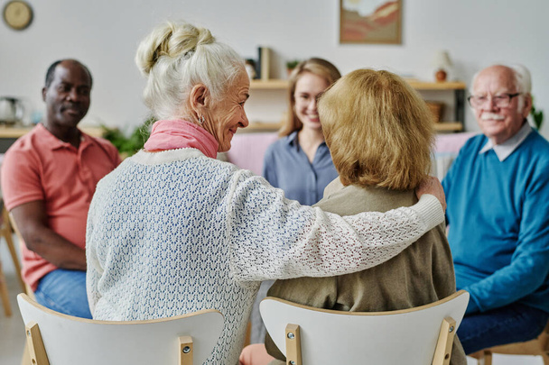 Задний план пожилой женщины, поддерживающей своего друга во время сеанса психотерапии с другими пожилыми людьми - Фото, изображение