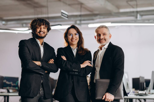Confident businesswoman in glasses posing with her business partners. Laughing business team posing in office together. High quality photo - Фото, зображення